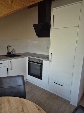 A kitchen with white cabinets, a black stove, and a wooden ceiling.