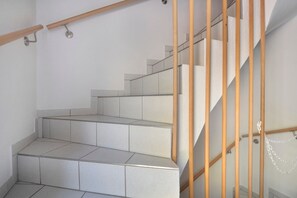 Una escalera con escalones de baldosas blancas y barandillas de madera.