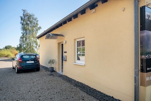 A building with a beige exterior, a car parked in front, a small window, and a door.