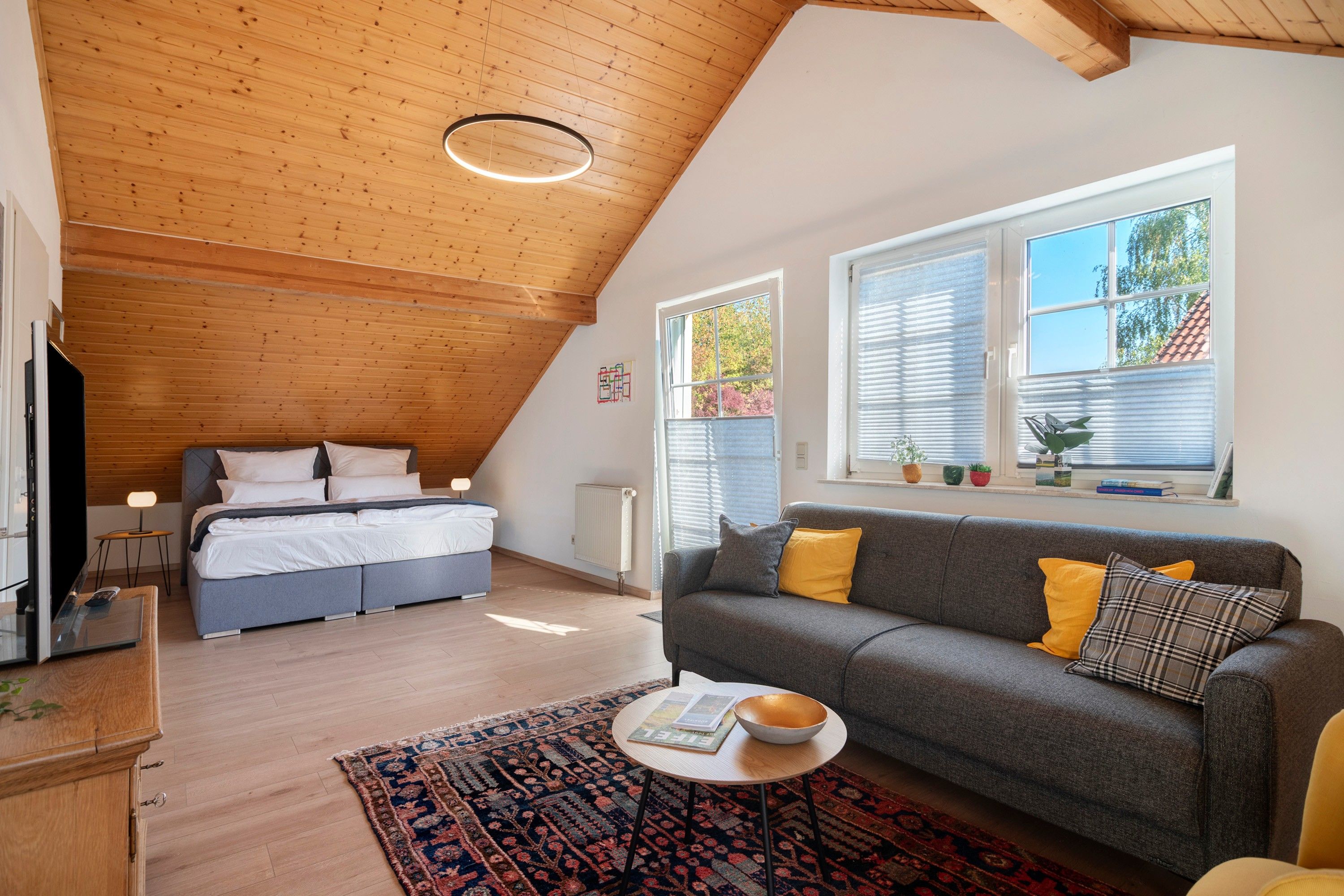 Une chambre de style loft moderne, avec un plafond en pente, un grand lit, un canapé et une petite table.