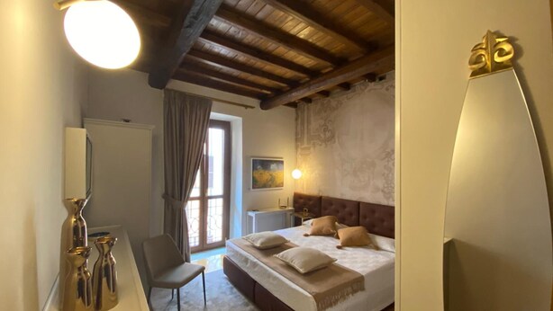 A bedroom with a bed, bedside table, chair, and a large mirror.