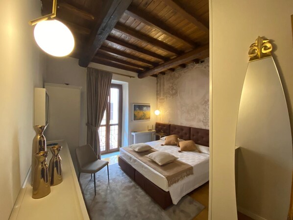 A bedroom with a bed, bedside table, chair, and a large mirror. - Rhona's Rooms B&B (Rome)