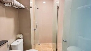 A modern bathroom with a glass shower enclosure, a white sink, and a toilet. - New Waigo Hotel (Sorong)