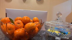 A bowl of oranges, a glass container with a lid, and a laptop on a table. - New Waigo Hotel (Sorong)