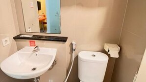 A bathroom with a sink, toilet, and a towel rack. - New Waigo Hotel (Sorong)