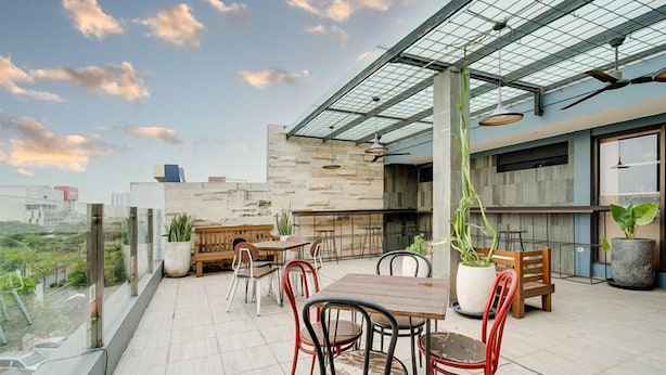 An outdoor terrace with a dining area, potted plants, and a view of the cityscape. - Life Hotel Sidoarjo (Sidoarjo)