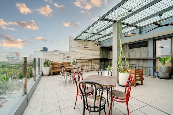 An outdoor terrace with a dining area, potted plants, and a view of the cityscape. - Life Hotel Sidoarjo (Sidoarjo)