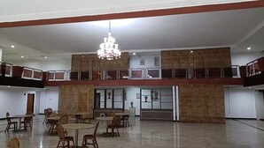 Ein geräumiger Saal mit mehreren Tischen und Stühlen, einer Kristallleuchter und einem Balkon.