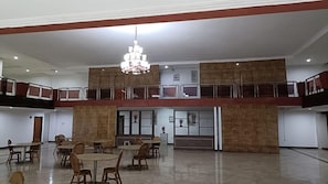 Un amplio salón con varias mesas y sillas, un candelabro y un balcón.