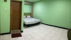 Ein Zimmer mit einem Bett, einer Tür und einem Fliesenboden.