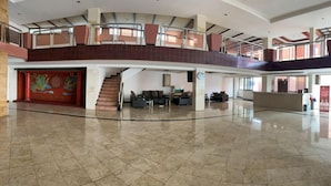 Eine geräumige Lobby mit hoher Decke, einer Treppe und einem Empfangsbereich.