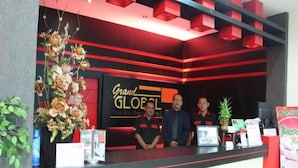 Um balcão de recepção com uma placa que diz 'Grand GLOBE The Business Hotel'.