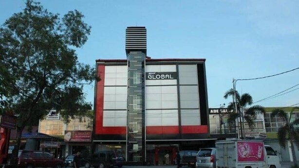 Um edifício com uma placa chamativa 'GLOBAL', uma estrutura vertical imponente e fachada em vermelho e branco.