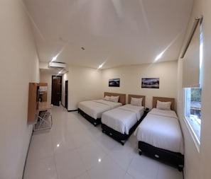 A hotel room with three beds, a desk, and a window. - Hotel Lumba-lumba inn Waru (Surabaya)