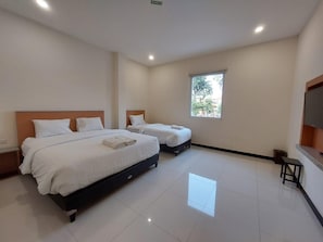 A hotel room with two beds, a window, a flat-screen TV, and a small table. - Hotel Lumba-lumba inn Waru (Surabaya)