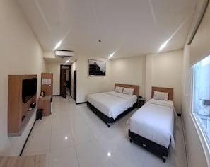 A hotel room with two beds, a TV, a desk, and an air conditioning unit. - Hotel Lumba-lumba inn Waru (Surabaya)