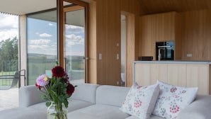 A modern living room with a sofa, a vase of flowers, and a view of the outdoors. - Apartment 'Ruhige Dachgeschoss-Wohnung' with Panoramic Green View, Balcony and Parking (Bad Dürrheim)