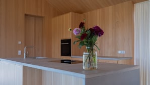 A modern kitchen with a wooden interior, a built-in sink, and a vase with flowers on the countertop. - Apartment 'Ruhige Dachgeschoss-Wohnung' with Panoramic Green View, Balcony and Parking (Bad Dürrheim)