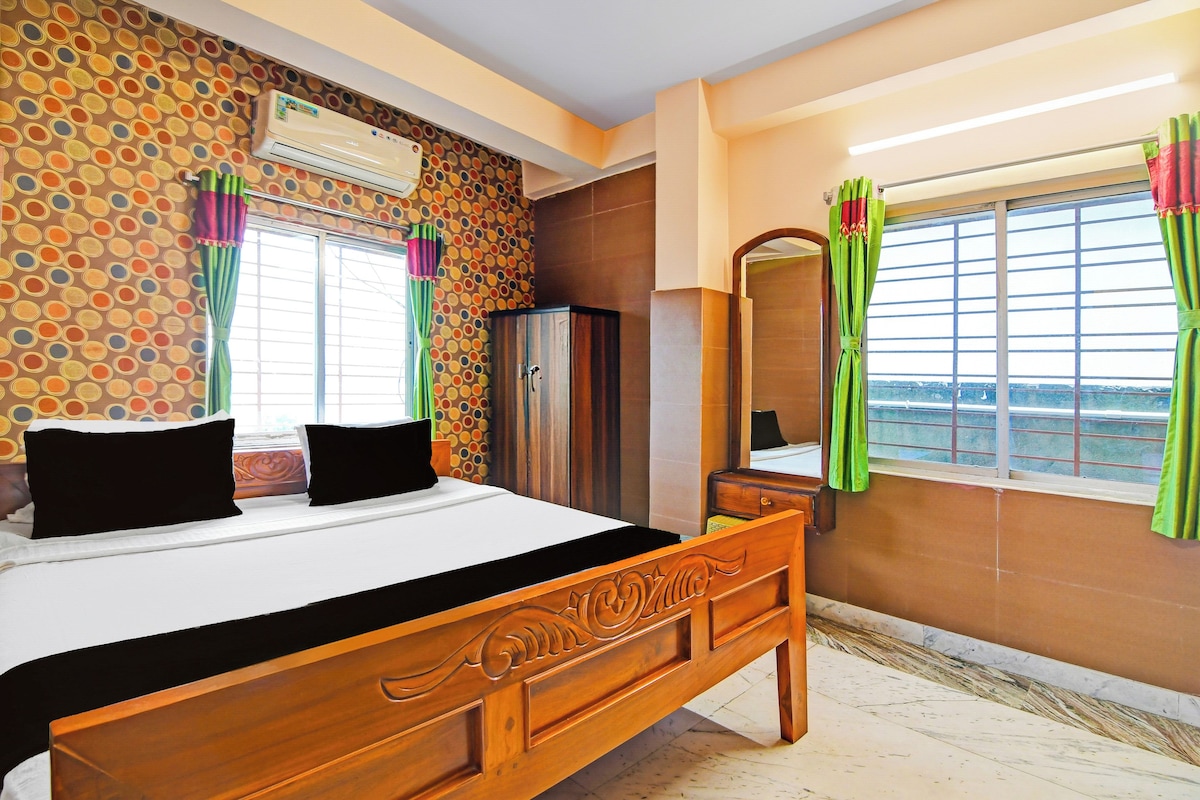 A hotel room with a bed, a wardrobe, a mirror, and a window with curtains.