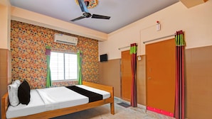 Ein Zimmer mit einem Bett, einem Deckenventilator, einem Fenster mit Vorhängen, einer Wandklimaanlage und einer Tür mit einem Vorhang.