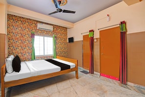 A room with a bed, a ceiling fan, a window with curtains, a wall-mounted air conditioner, and a door with a curtain. - Super Hotel O Rishra Railway Station (Kolkata)