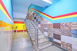 A staircase with a metal railing leading to a tiled wall with various patterns.