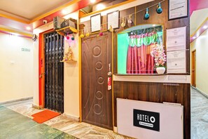 A hotel entrance with a wooden door, a reception desk, and a sign indicating it's a company-serviced hotel.