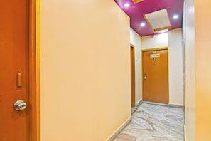 A hotel corridor with a marble floor, a wooden door labeled 'CLASSIC ROOM 7', and a ceiling with recessed lighting.