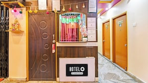 Ein Hotel-Empfangsbereich mit einem Holzbuchungstresen, einem Schild mit der Aufschrift 'HOTEL' und einer Treppe zu den Zimmern.