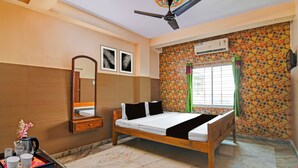 Ein Hotelzimmer mit Bett, Spiegel, Deckenventilator, Fenster mit Vorhängen und Wand mit einem Rundmuster.