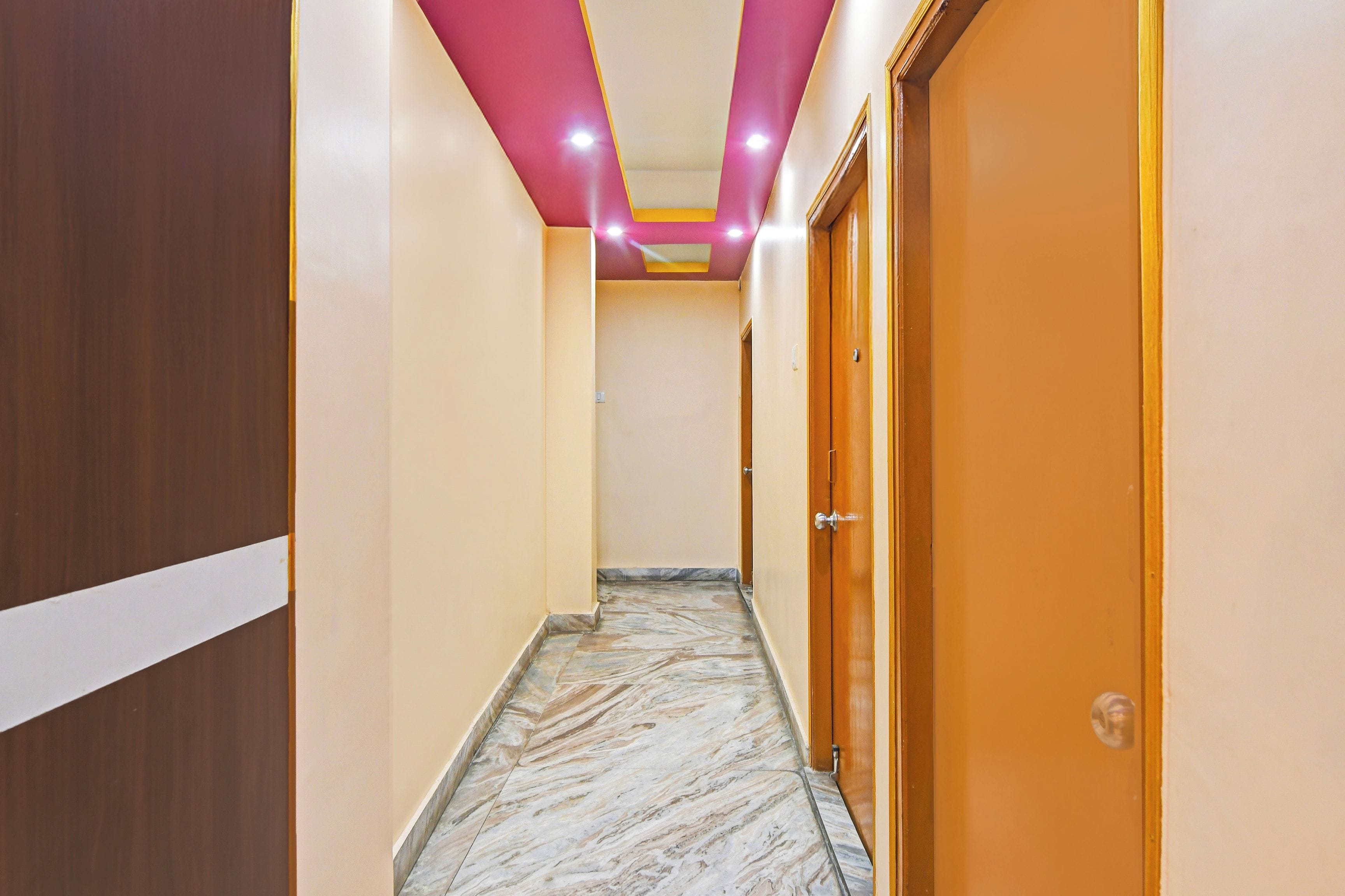 Un pasillo con suelo de mármol, puertas de madera e iluminación empotrada en el techo.