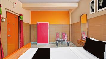 A hotel room with a bed, a bathroom with a mirror, and a door.