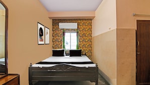 Ein Schlafzimmer mit einem Bett, einem Kleiderschrank, einem Spiegel und einem Fenster mit Vorhängen.