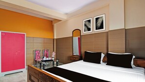 Ein Hotelzimmer mit einem Bett, einem Schminktisch mit Spiegel und einem roten Kleiderschrank.