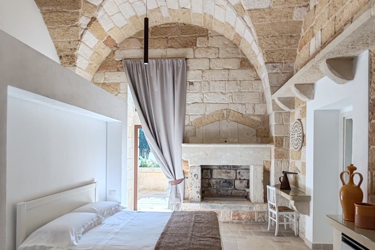A bedroom with a stone ceiling, a bed, a fireplace, and a view of the outdoors.