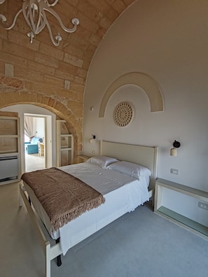 A bedroom with a bed, a chandelier, an arched doorway, and a circular wall decoration.