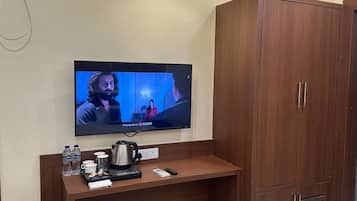 A television mounted on a wall with a wooden cabinet beside it.