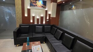 A modern hotel lobby with a black leather sofa, a glass coffee table, and a framed picture on the wall. -  Aristo Inn B&B (Varanasi)