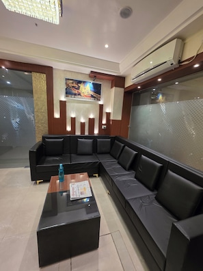 Un moderno hall de hotel con un sofá de cuero negro, una mesa de centro de vidrio y un cuadro en la pared.