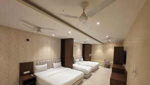 A hotel room with two beds, a TV, a desk, and a ceiling fan. -  Aristo Inn B&B (Varanasi)