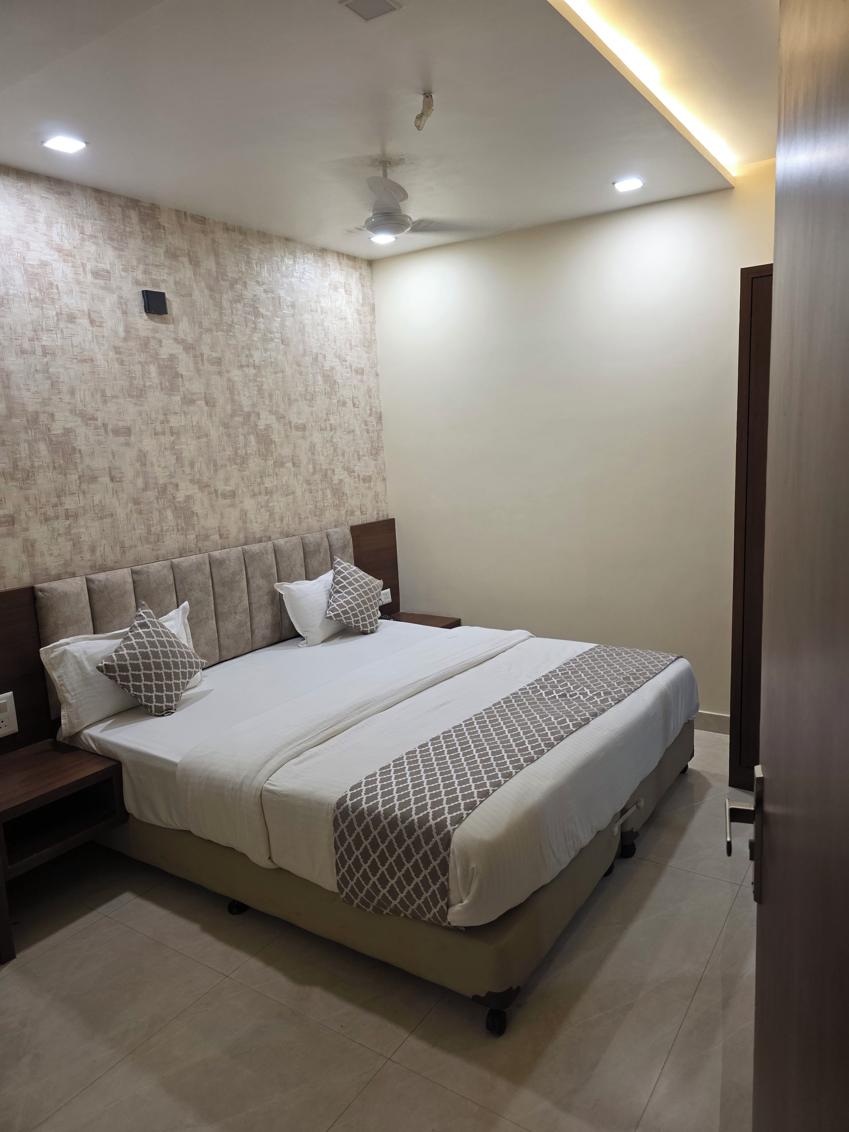A bedroom with a bed, nightstands, a ceiling fan, and recessed lighting.