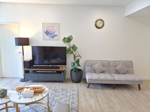 A living room with a flat-screen TV, a sofa, a coffee table, a lamp, and a potted plant. - Contemporary 2BDR APT with 2 Baths in Homebush (Homebush)