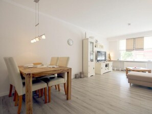 A modern living room with a dining area, a TV, and a window. - Holiday Apartment With 2 Bedrooms (Wyk auf Foehr)