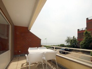 A balcony with a table and chairs, a view of the sea, and a brick wall. - Holiday Apartment With 2 Bedrooms (Wyk auf Foehr)