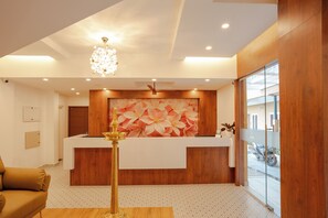 A reception area with a wooden reception desk, a chandelier, and a large floral wall mural.