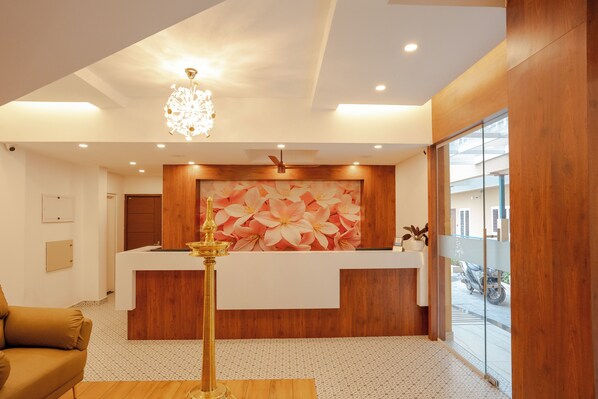 Un área de recepción con un mostrador de madera, una araña de cristal y un gran mural floral.