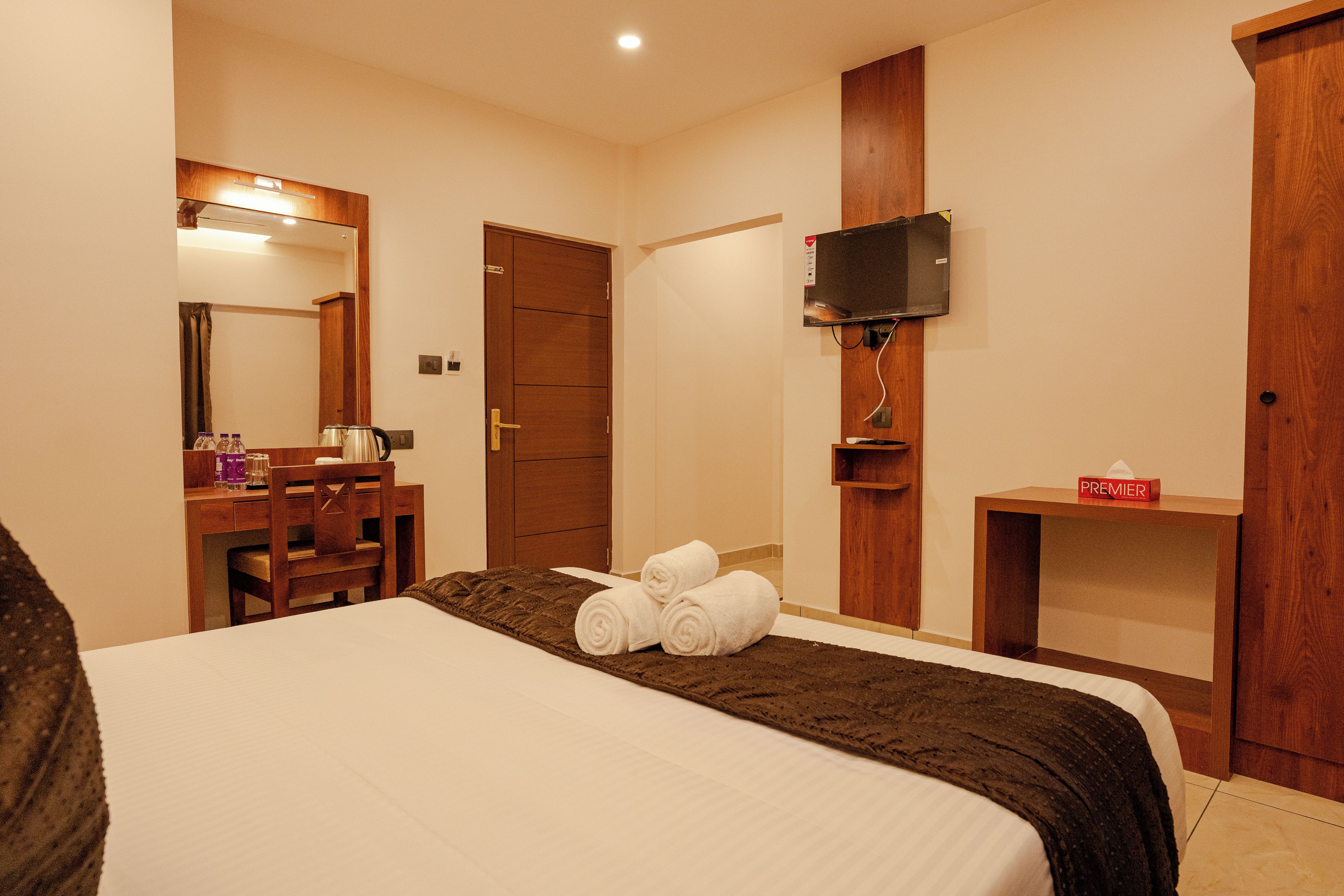 Une chambre d’hôtel équipée d’un lit, d’un bureau, d’une chaise, d’un téléviseur fixé au mur et d’une armoire.