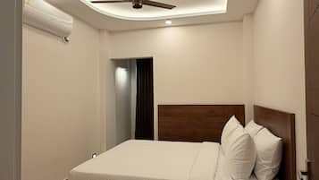 Un dormitorio moderno con ventilador de techo central, cama con ropa de cama blanca y armario empotrado.
