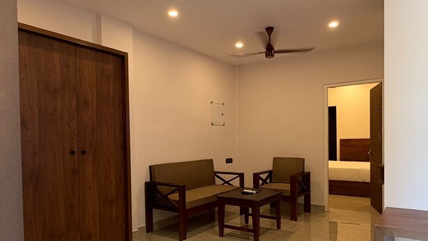 A room with a wooden wardrobe, a sofa, a coffee table, and a ceiling fan.