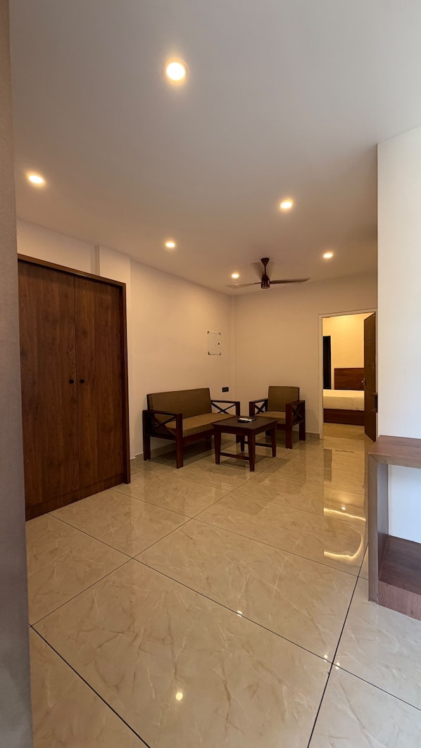 Una habitación con un armario de madera, un sofá, una mesa de centro y un ventilador de techo.